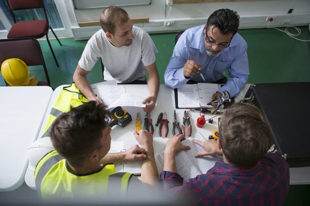 Electrician instructor sitting with students at table